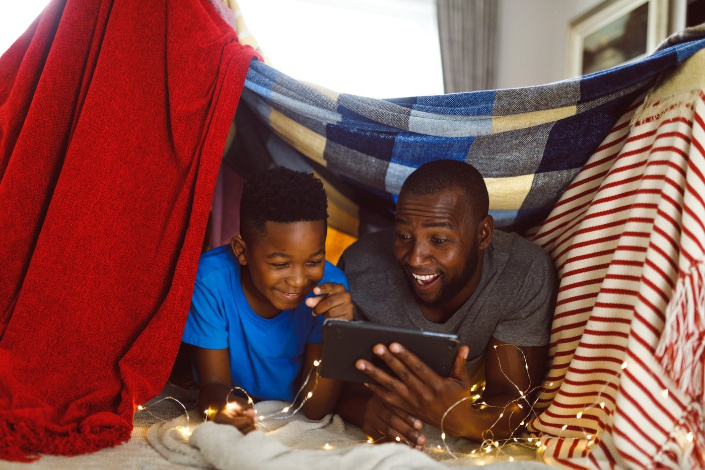 Father and son playing in a blanket fort at home