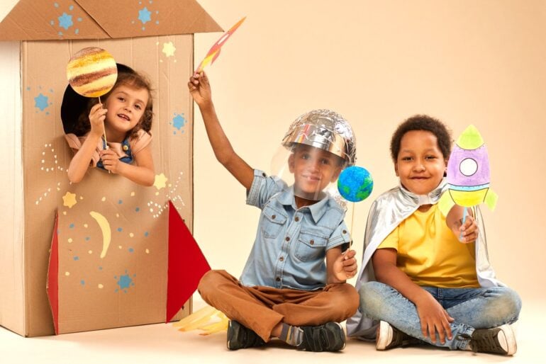 Kids playing with a DIY cardboard fort and costumes